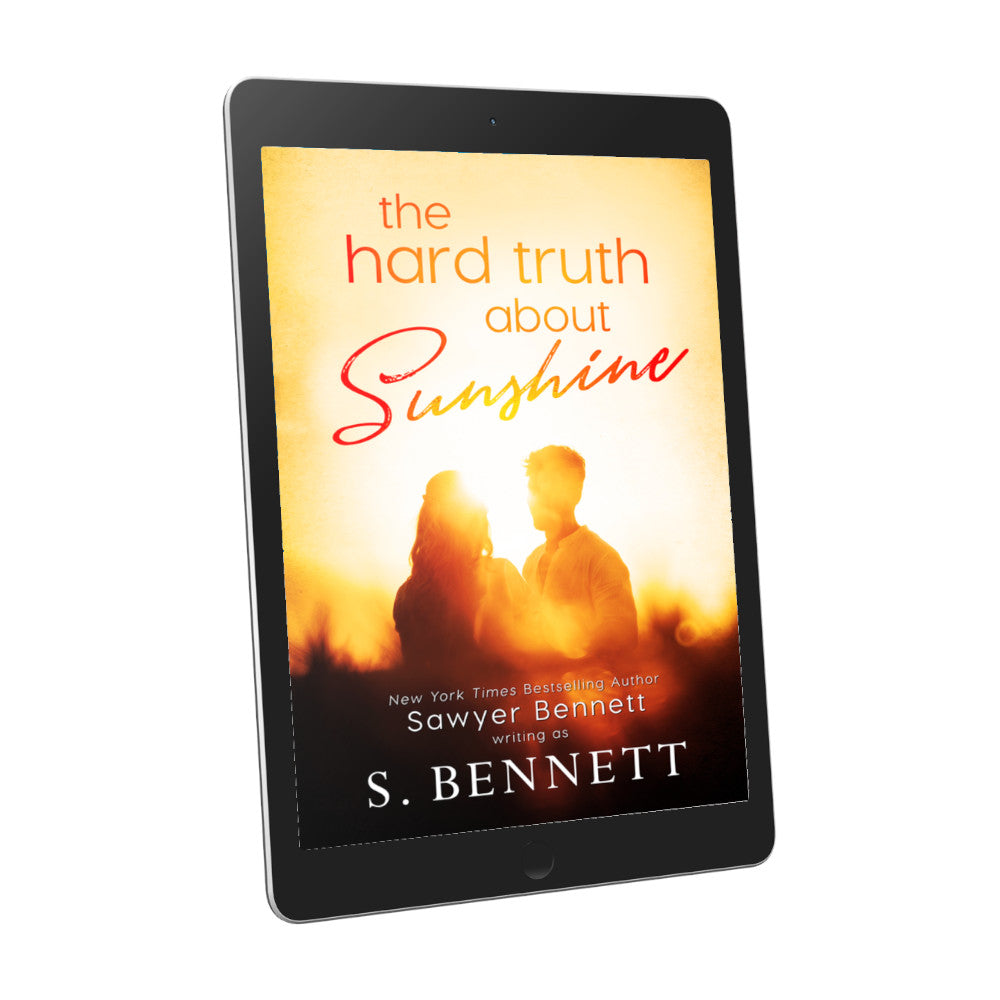A general fiction book cover featuring a couple embracing in the glow of the sunshine, the background blurred and shades of yellow and orange, displayed on an e-reader. The title of the book is The Hard Truth About Sunshine by New York Times Bestselling Author Sawyer Bennett.