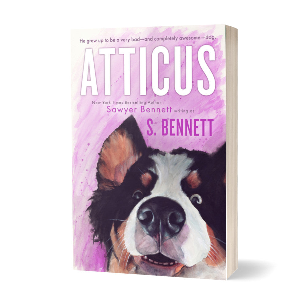 A woman’s fiction paperback featuring a watercolor painting of a Bernese Mountain Dog’s face. The dog has a slight smile on his face and his eyes are two different colors—one blue and one brown. The title of the book is Atticus by New York Times Bestselling Author Sawyer Bennett.