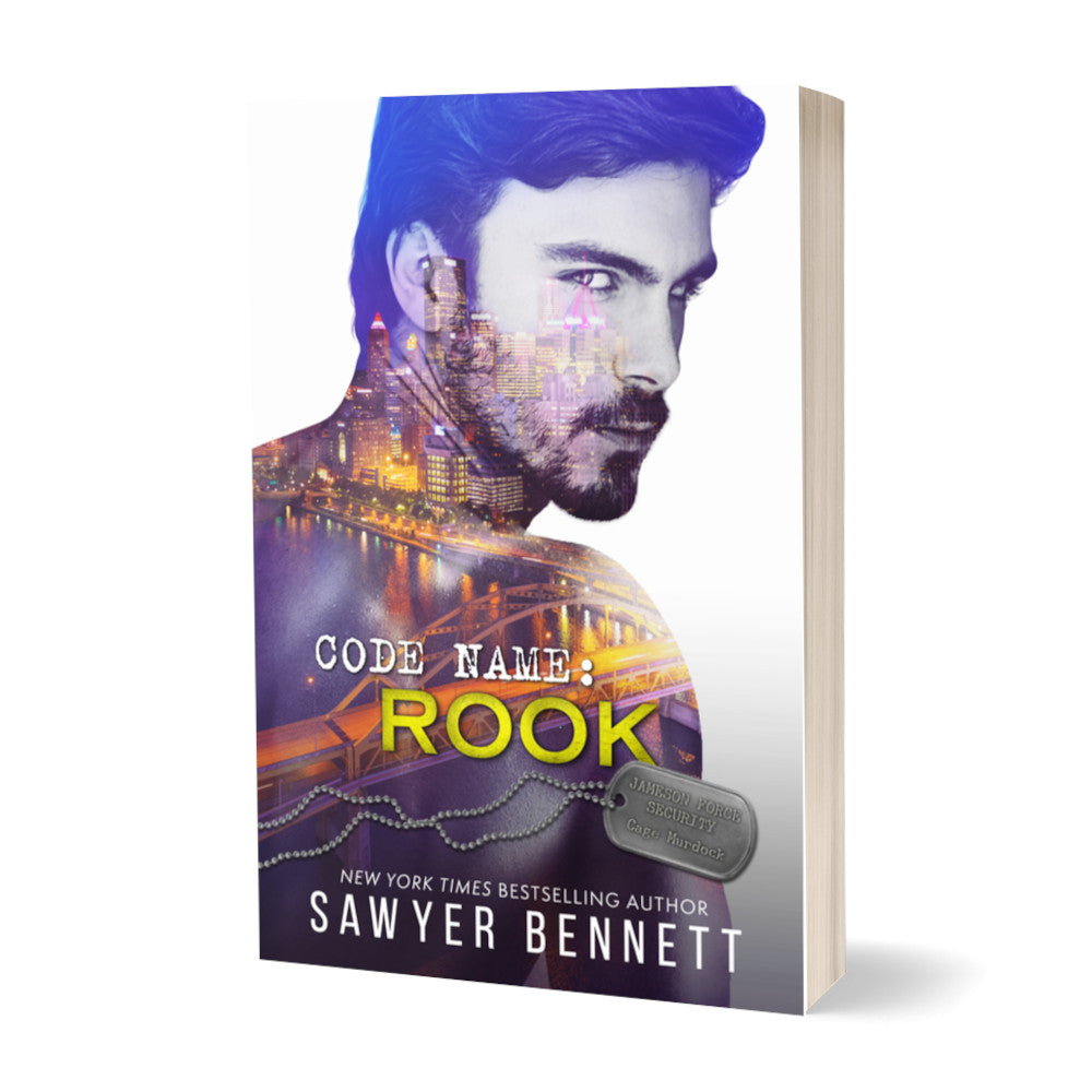 Romantic suspense paperback featuring an attractive man and city scape. The title of the book is Code Name: Rook by New York Times Bestselling Author Sawyer Bennett.