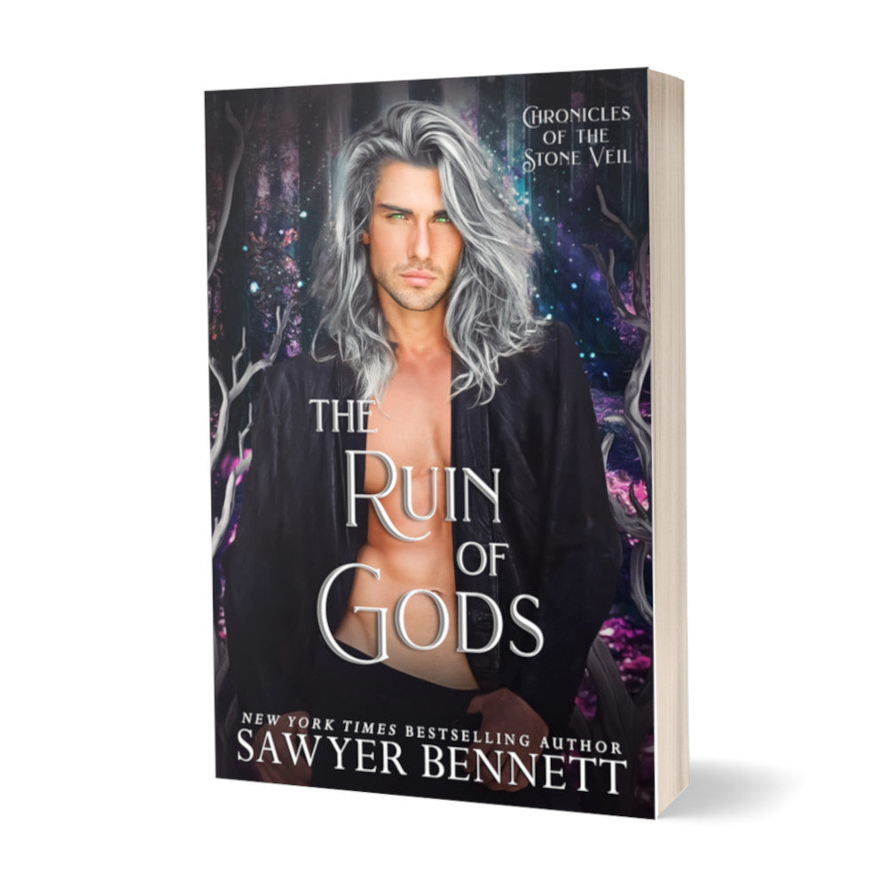 Fantasy romance paperback with a dark background with flecks of pinks, purples and blues and attractive man with long, gray hair wearing a black leather jacket open to reveal a bare chest. The title of the book is The Ruin of Gods by New York Times Bestselling Author Sawyer Bennett.